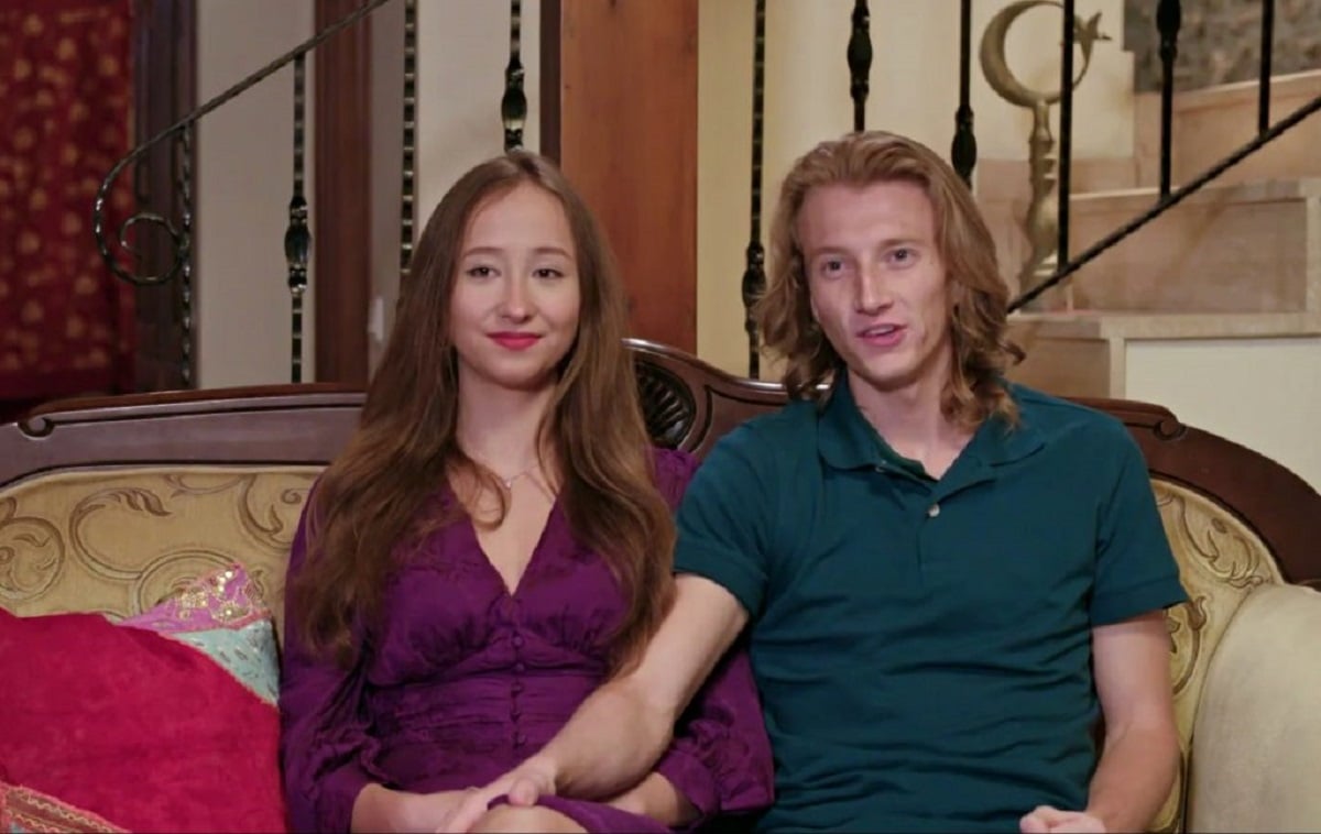 Alina and Steven on '90 Day Fiancé: The Other Way' -- Alina wears a purple dress, Steven a green polo. They sit on a couch facing the camera. Steven has his hand on her knee.