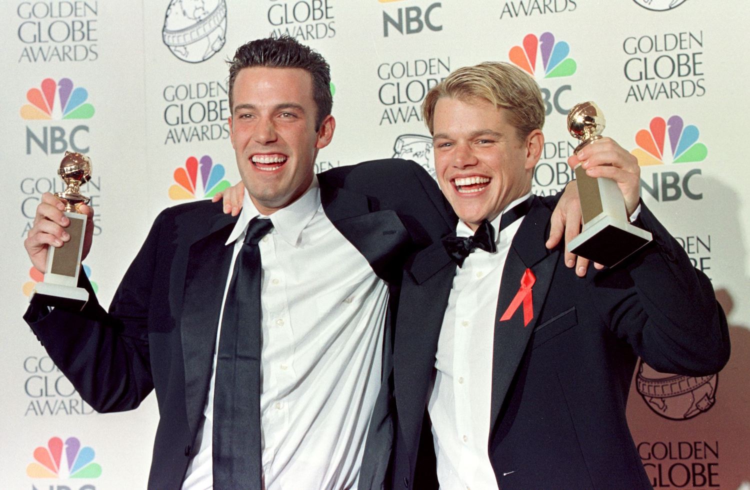 Matt Damon and Ben Affleck wear suits as they pose with their Golden Globe award for Best Screenplay for 'Good Will Hunting'