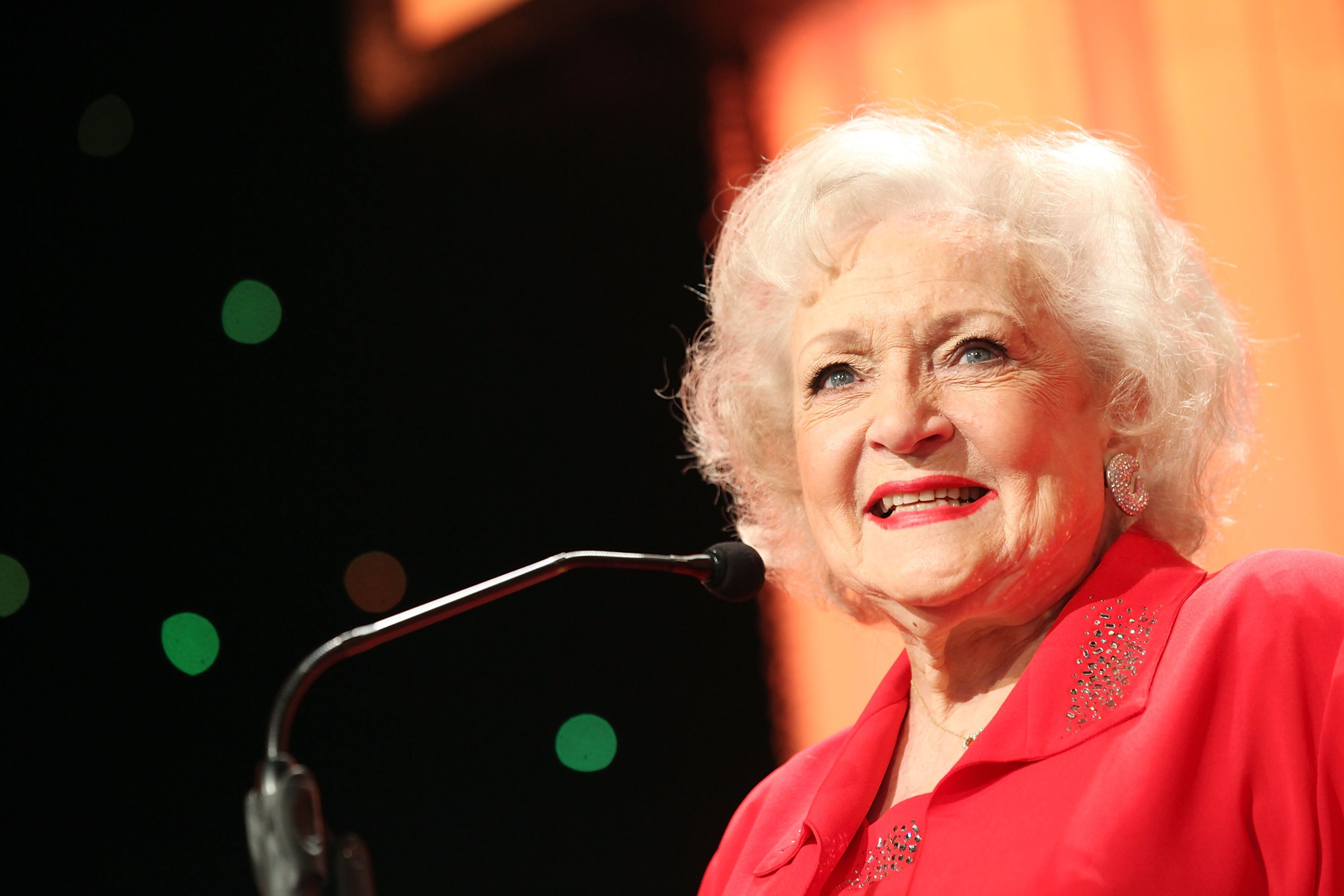 Betty White smiles while standing at a podium
