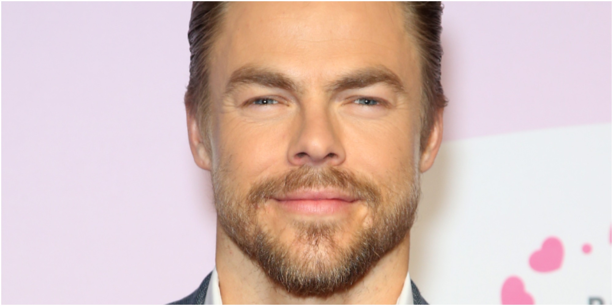 derek hough smiles for the camera on the red carpet