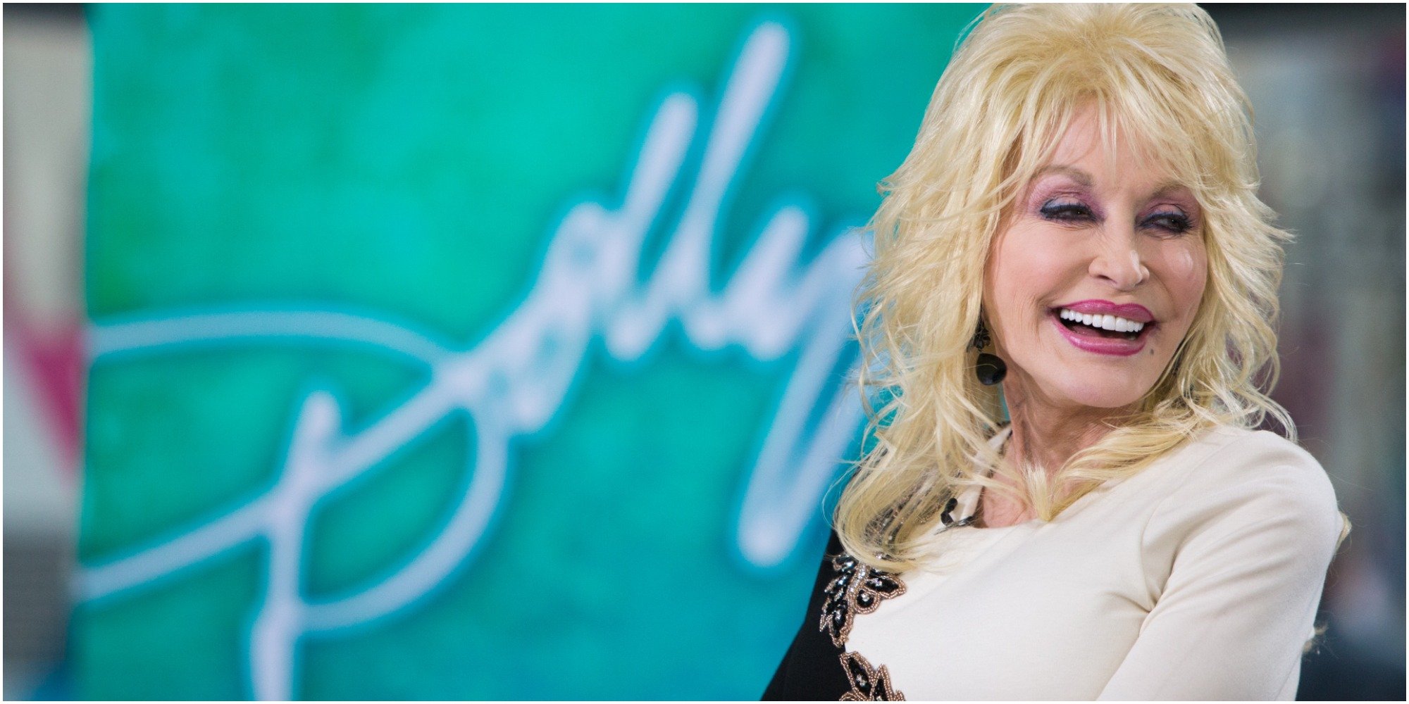 Dolly Parton smiles in a black and white dress.