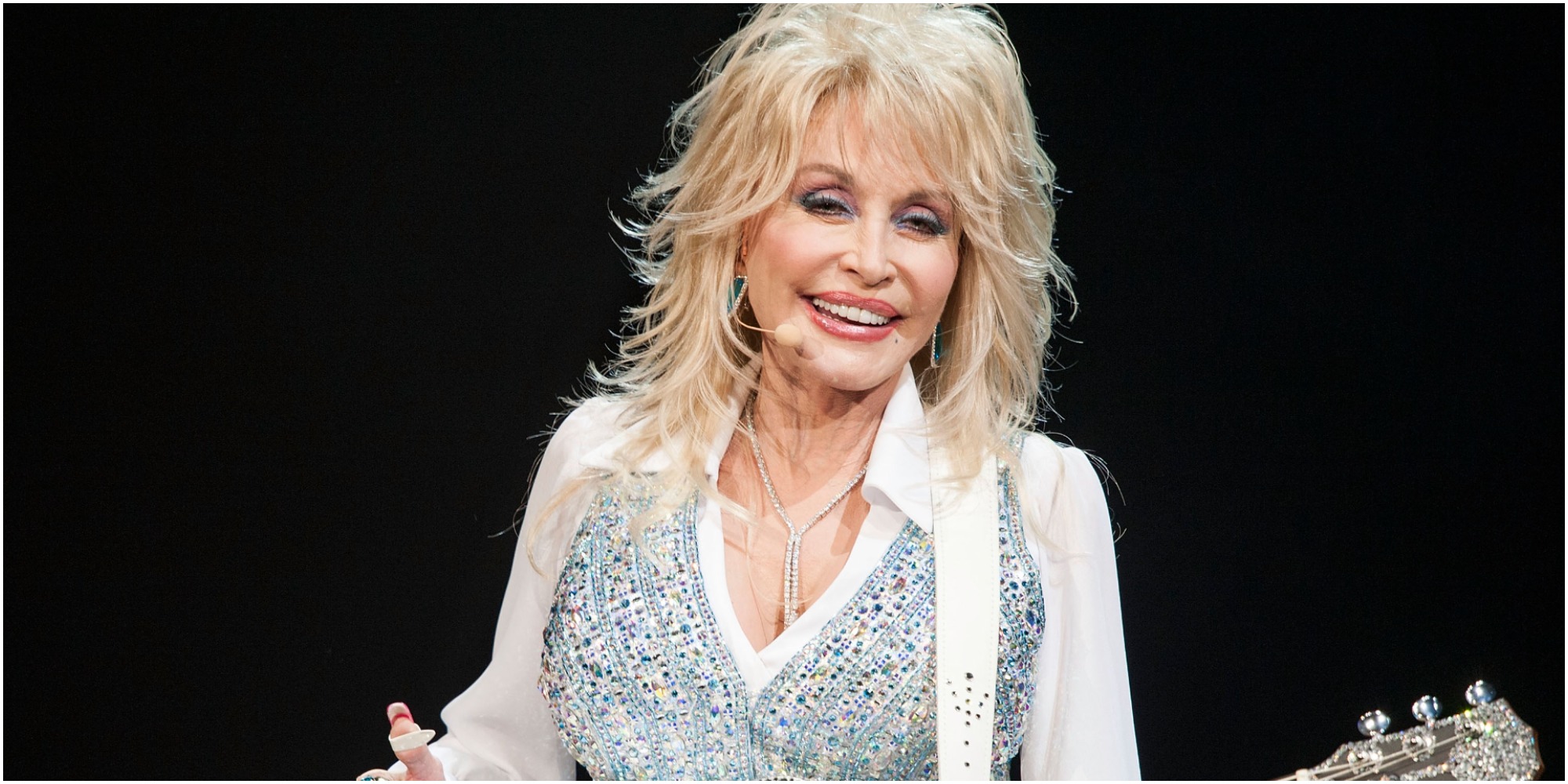 Dolly Parton poses with a guitar.