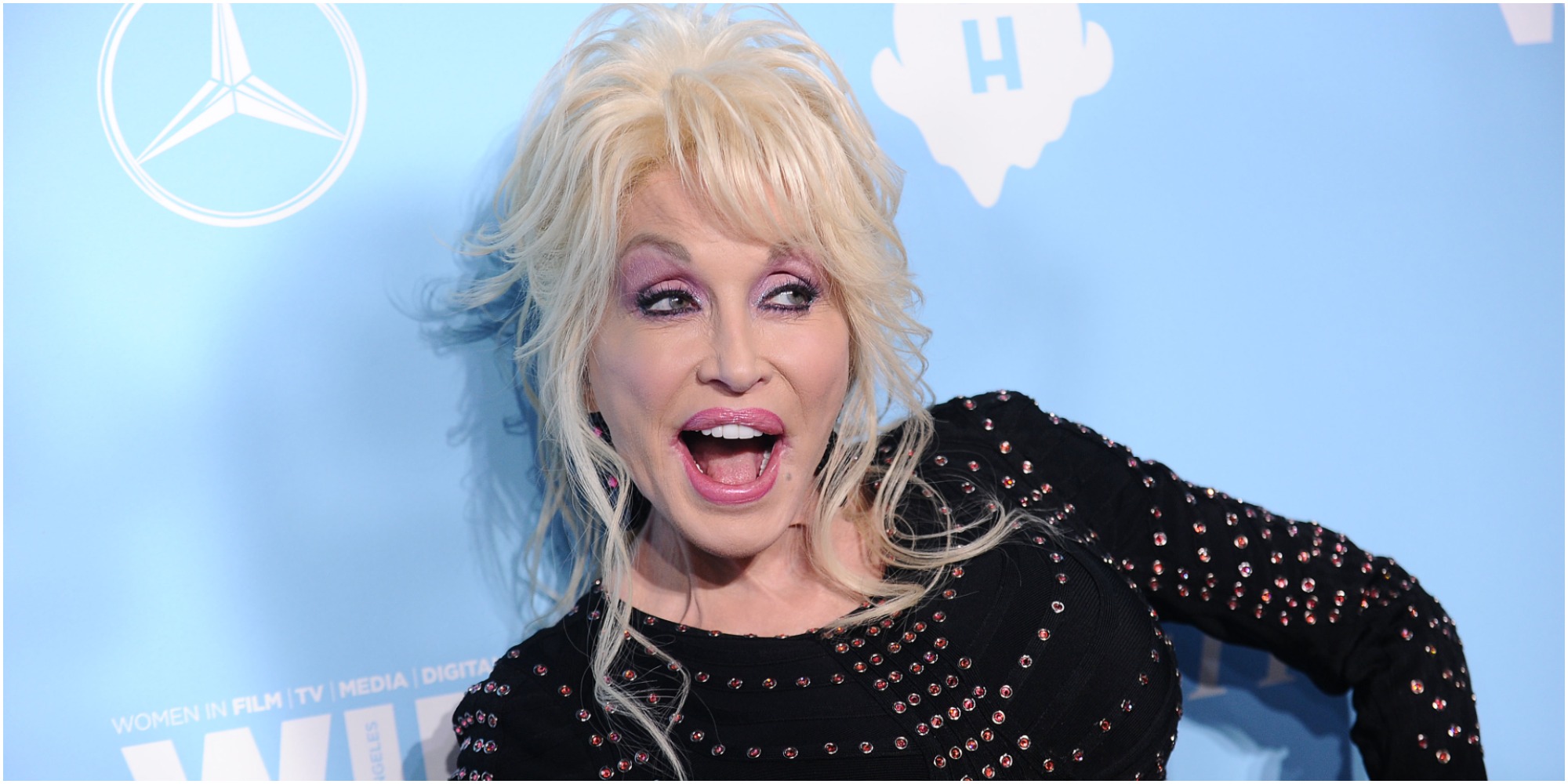 Dolly Parton takes a photo with her mouth open.