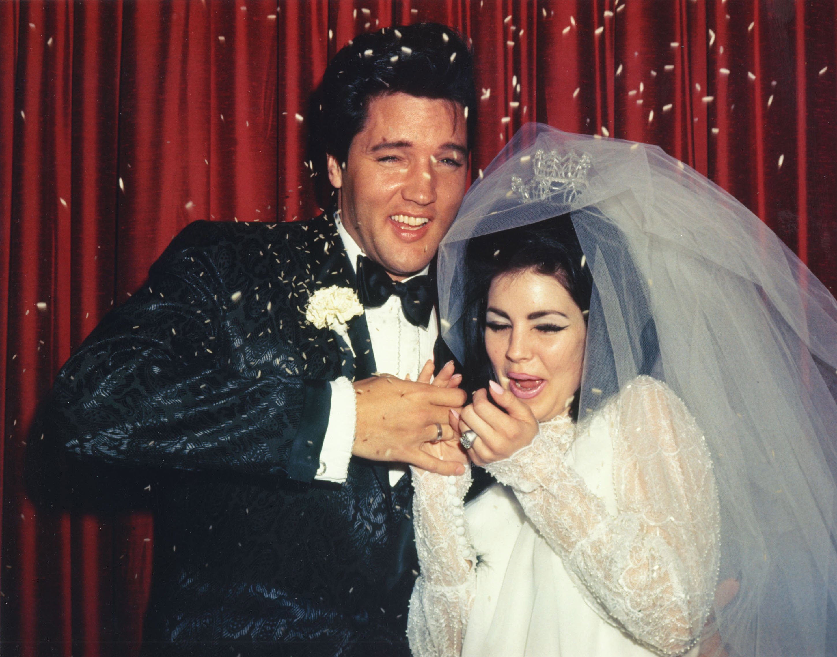 Elvis and Priscilla Presley in front of a red curtain