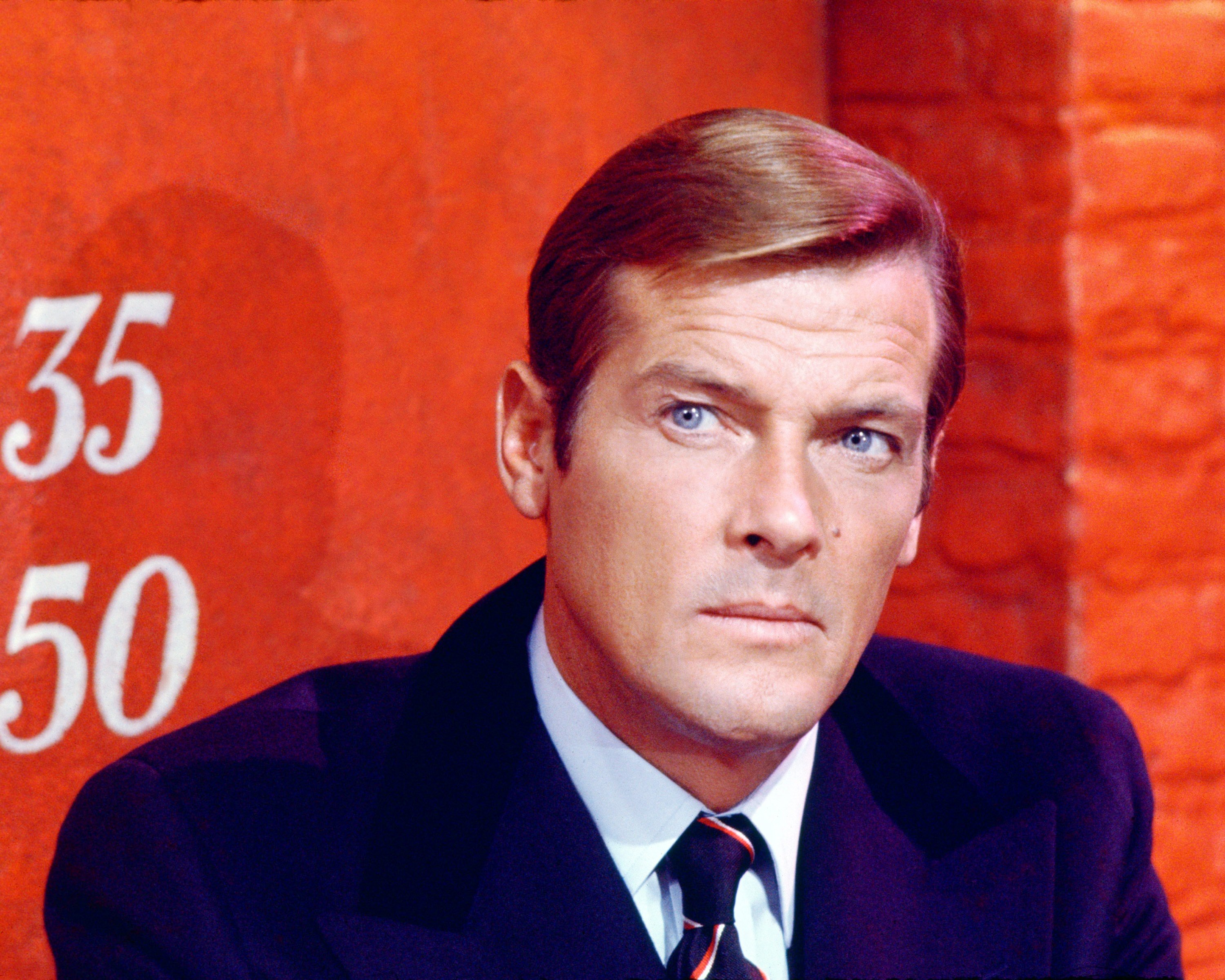 Roger Moore as James Bond in front of a red background