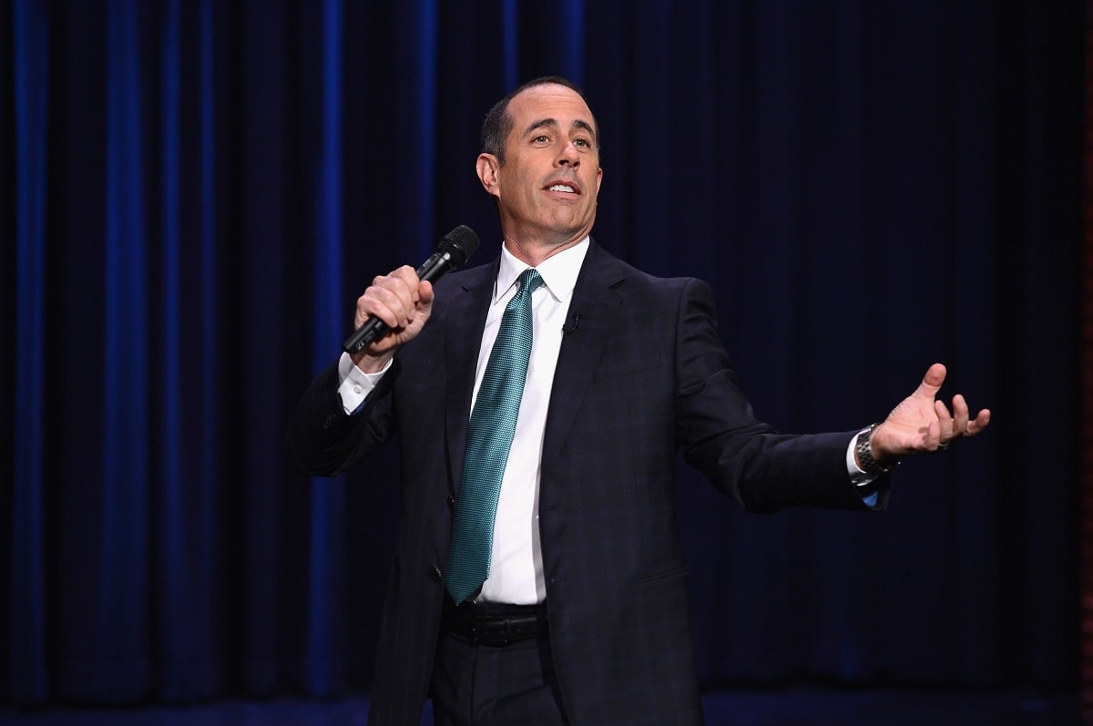 Jerry Seinfeld performing a comedy routine in a suit. 