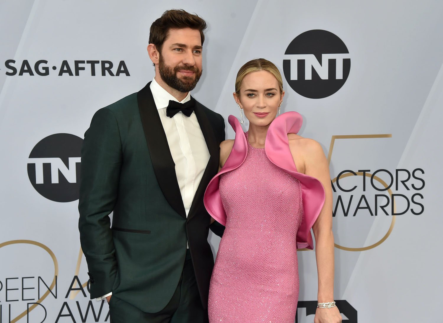 John Krasinski wears a tuxedo and Emily Blunt wears a pink dress with ruffle accents at the 2019 Screen Actors Guild Awards red carpet