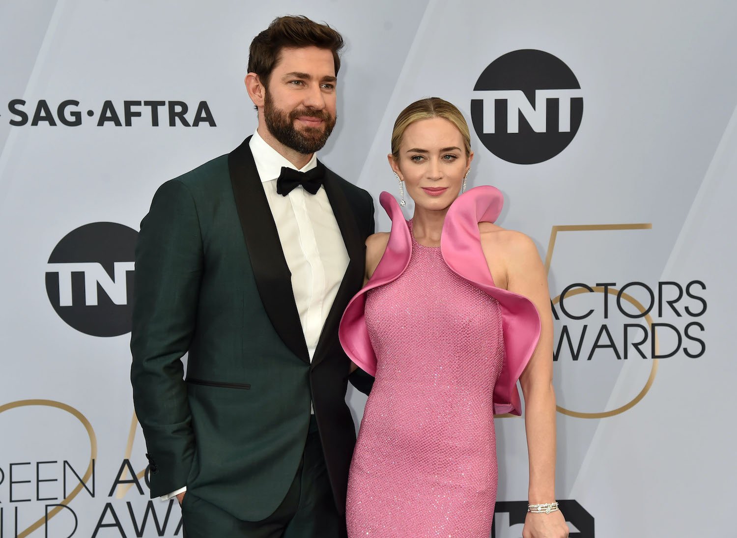 John Krasinski wears a tuxedo and Emily Blunt wears a pink dress with ruffle accents at the 2019 Screen Actors Guild Awards red carpet