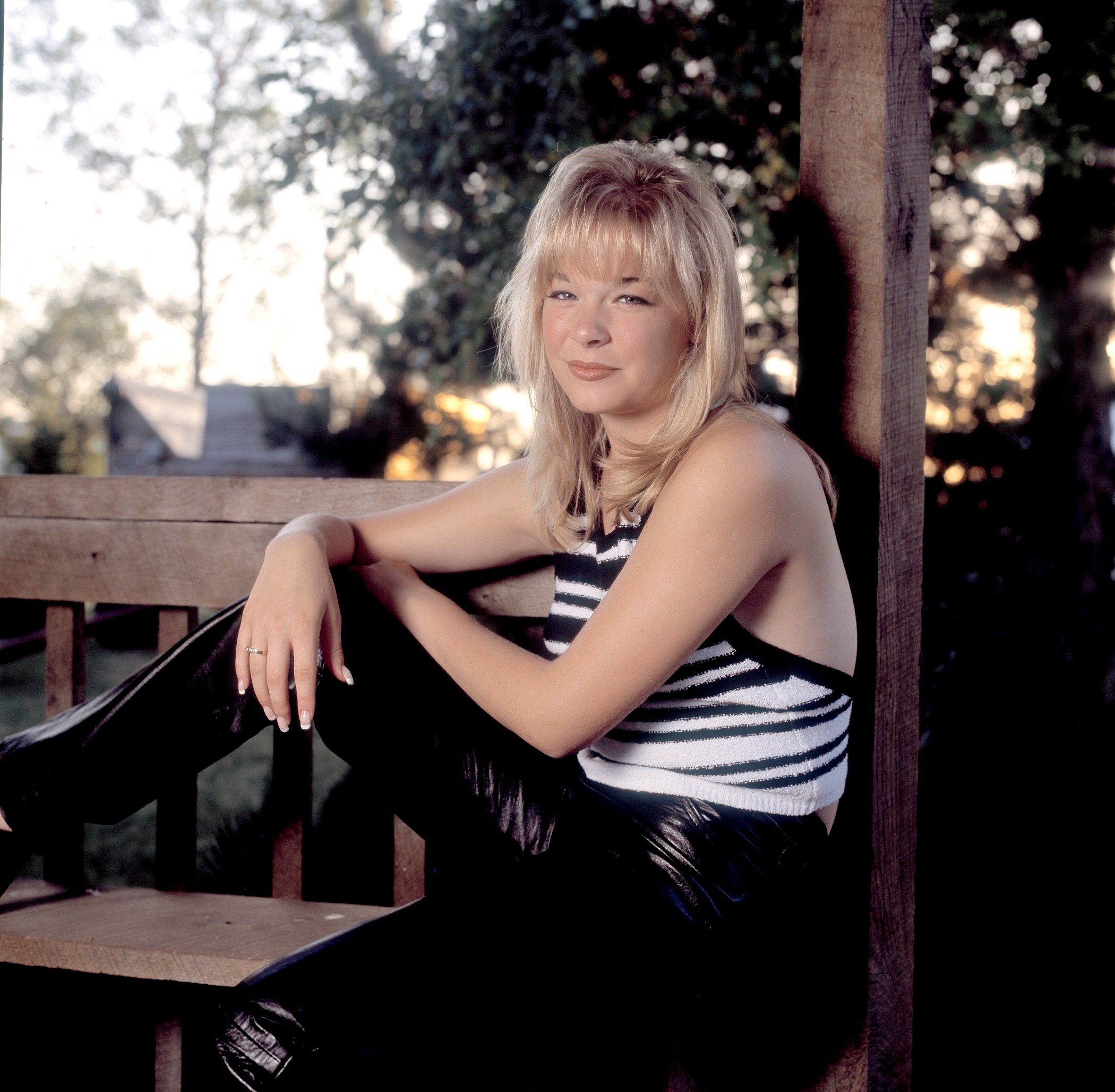 How Do I Live singer LeAnn Rimes sitting on a bench wearing a striped top