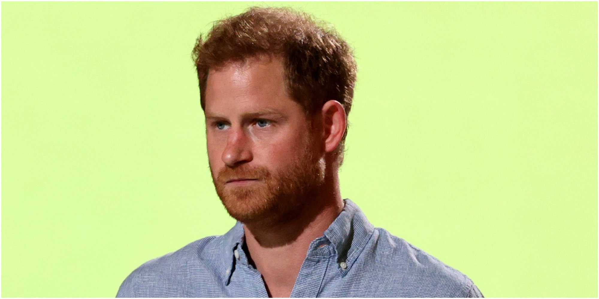 Prince Harry wears a blue shirt and stands in front of a yellow backdrop.
