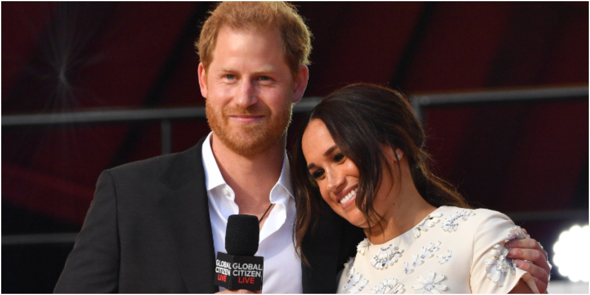 Meghan Markle wears a white dress and leans her head on Prince Harry who is wearing a suit with his shirt partially unbuttoned at the Global Citizen concert in Central Park on September 25, 2021 in New York City.
