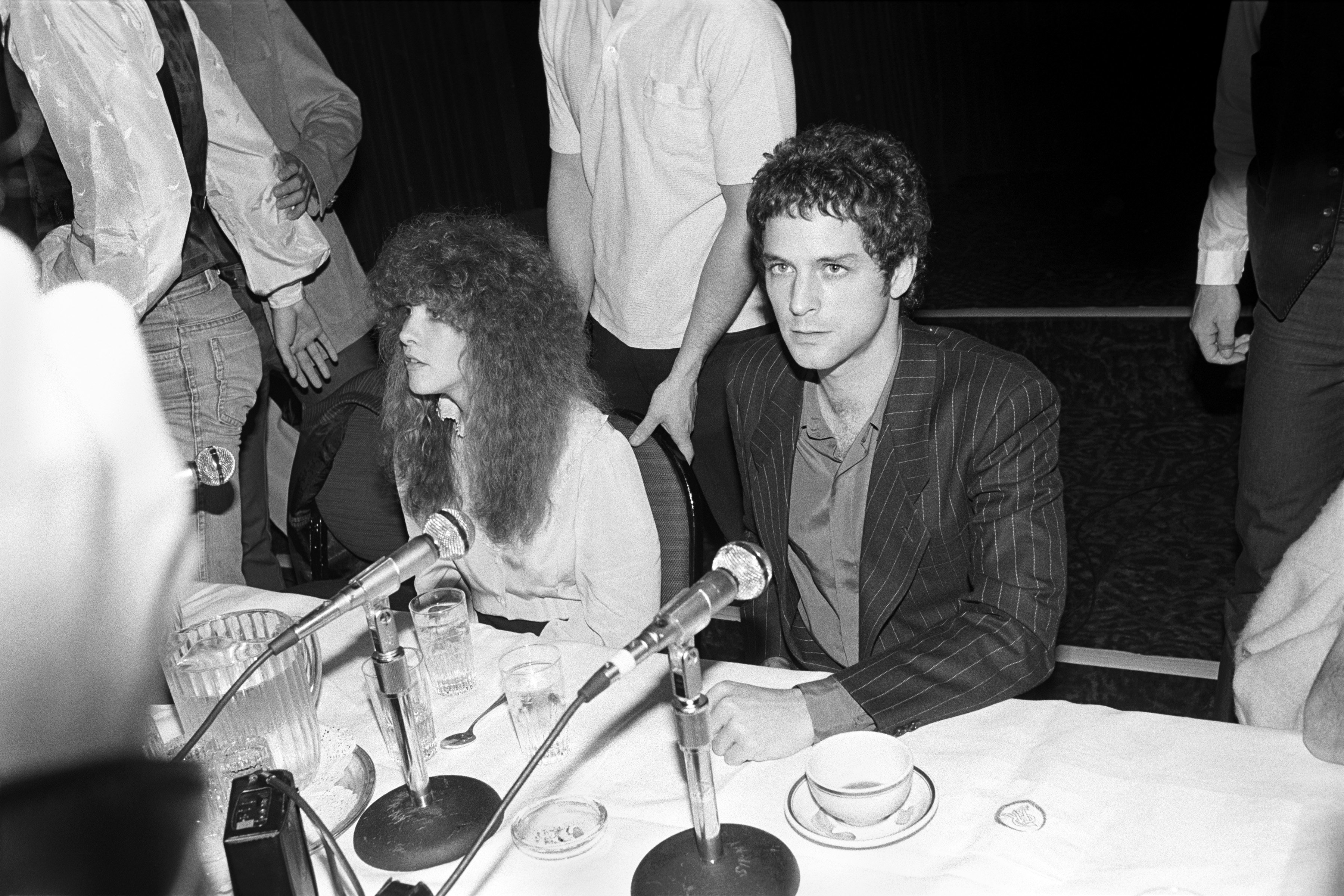 Stevie Nicks and Lindsey Buckingham sit at a table with microphones.