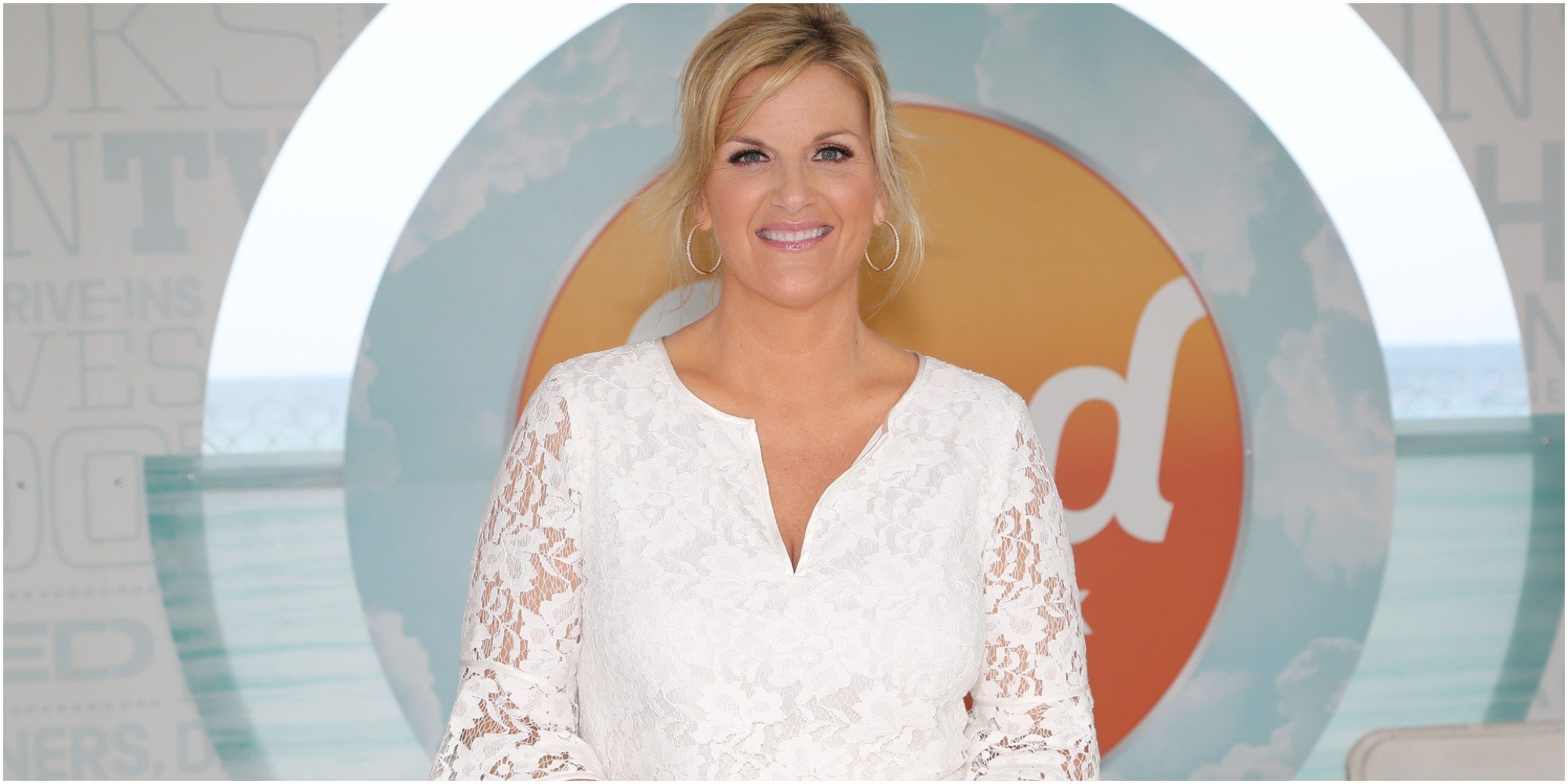 Trisha Yearwood poses in front of the Food Network logo.