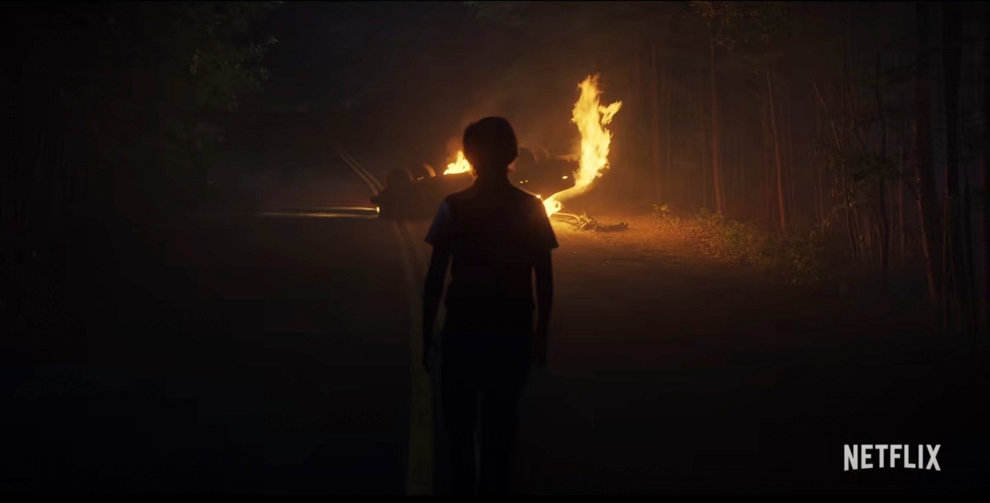 Mystery person standing in front of a burning car from the 'Stranger Things' Season 4 sneak peek, fans think we'll see a lot of 'A Nightmare on Elm Street' in the upcoming season.