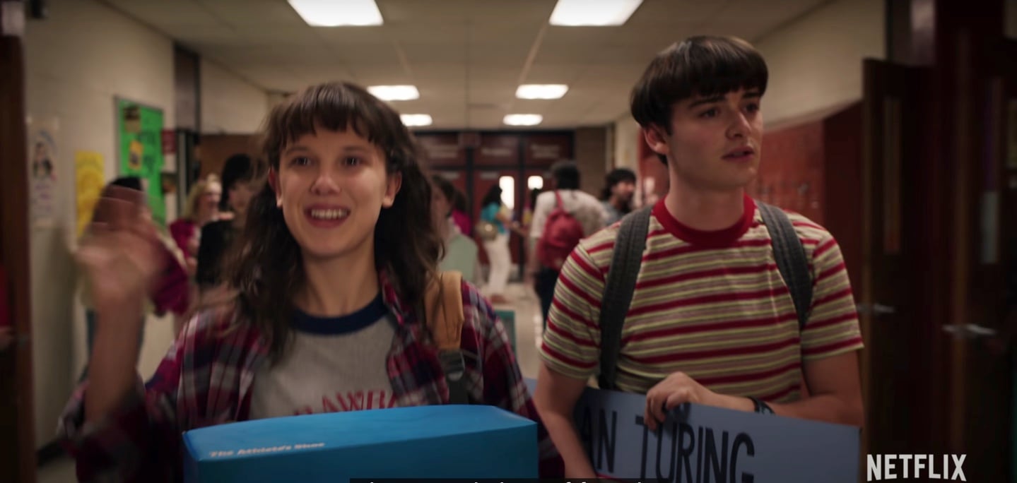 Noah Schnapp and Millie Bobby Brown walking down the hall at their new school in California in a scene from Stranger Things Season 4.