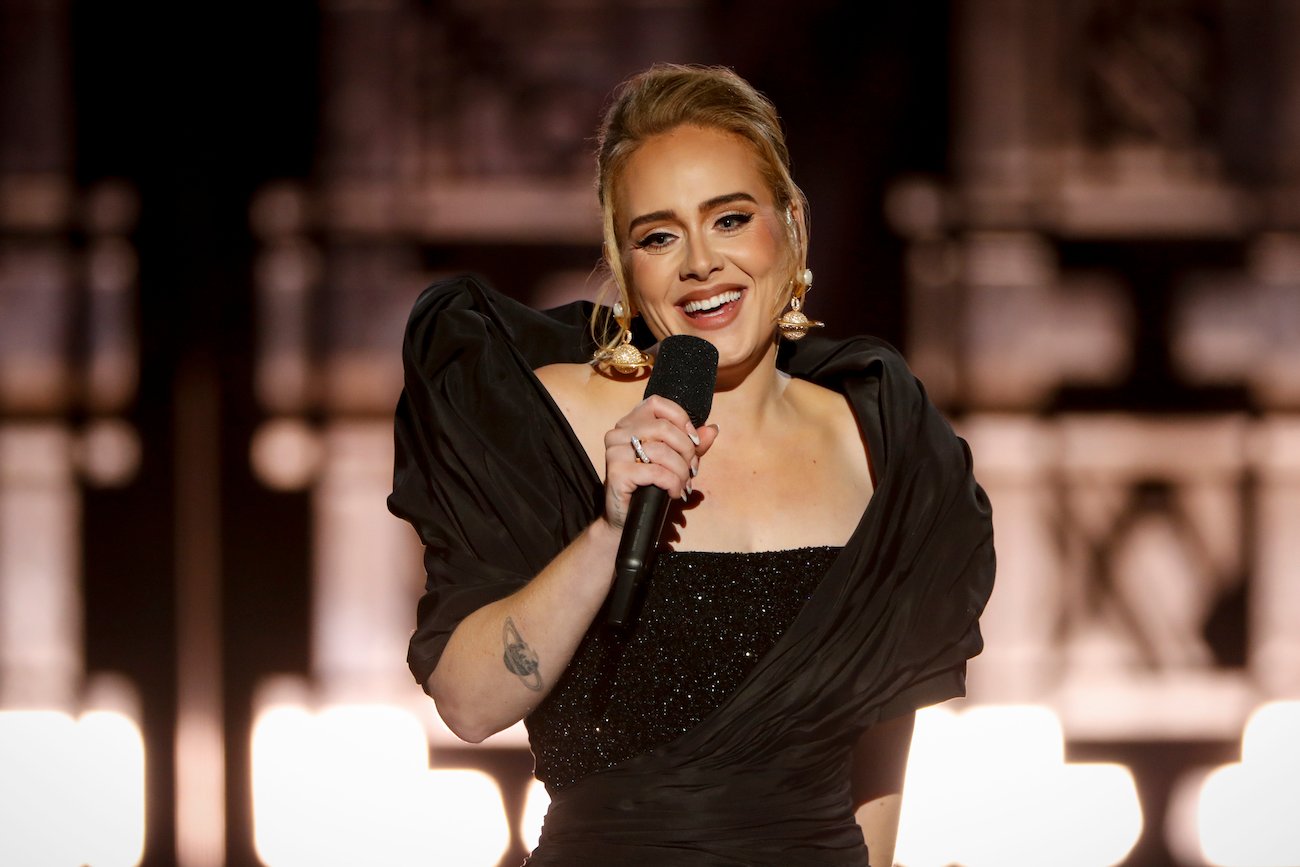Adele wearing a black dress speaking into a microphone
