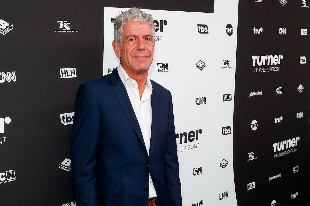 Anthony Bourdain smiling in front of a black and white background