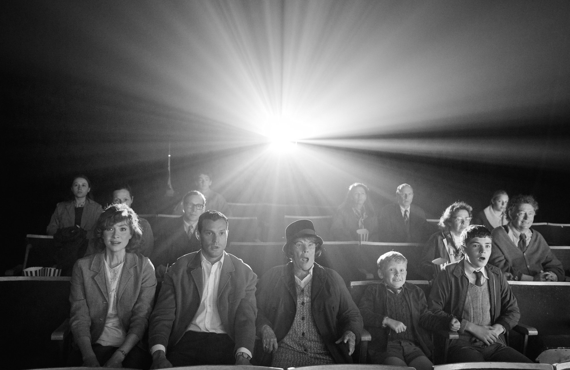 'Belfast' stars Caitriona Balfe as Ma, Jamie Dornan as Pa, Judi Dench as Granny, Jude Hill as Buddy, and Lewis McAskie as Will sitting in a movie theater looking surprised