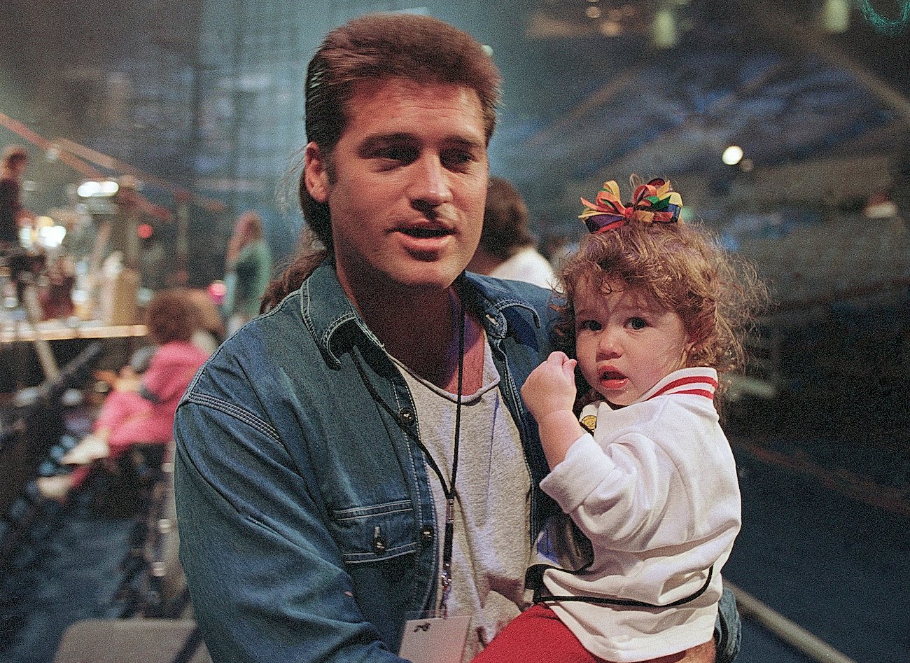 Billy Ray Cyrus holding toddler Miley Cyrus in 1994