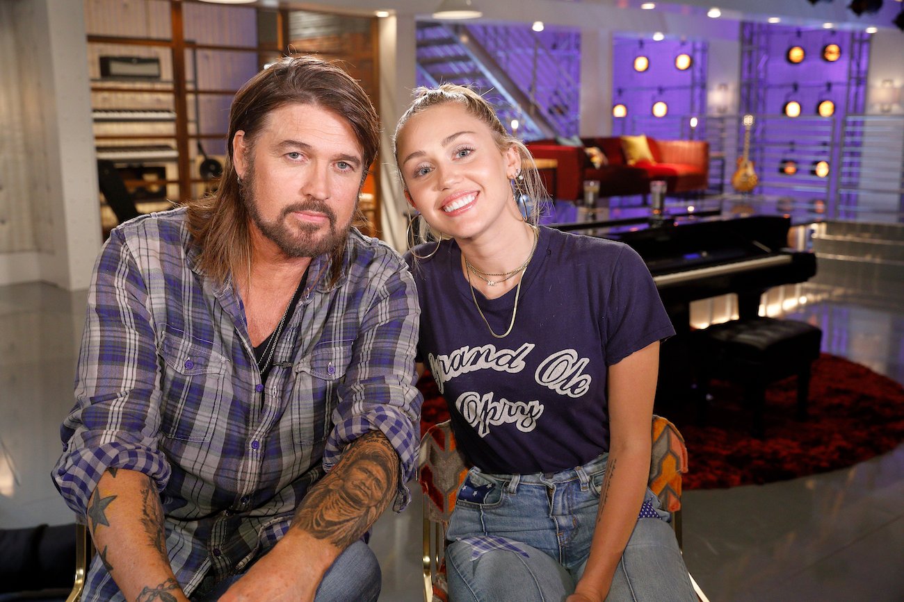 Billy Ray Cyrus and Miley Cyrus sitting together behind the scenes of 'The Voice' in 2017