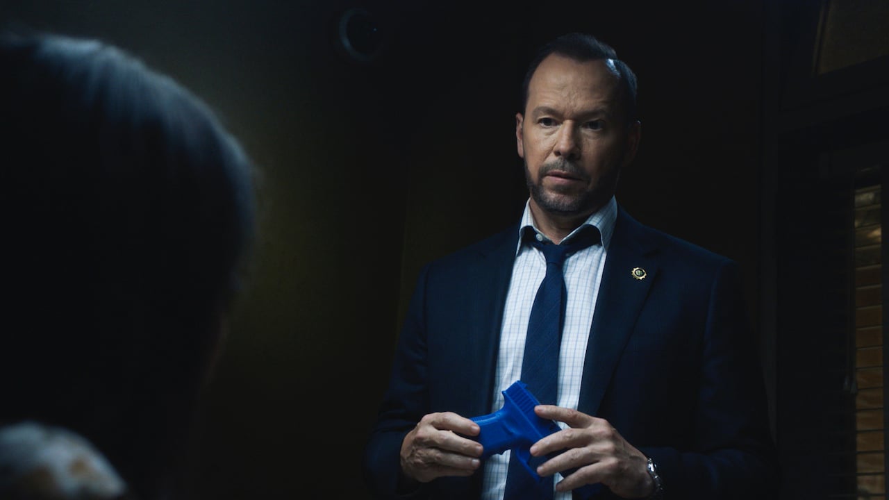 Donnie Wahlberg as Danny Reagan on 'Blue Bloods' stands in a suit taking off gloves.