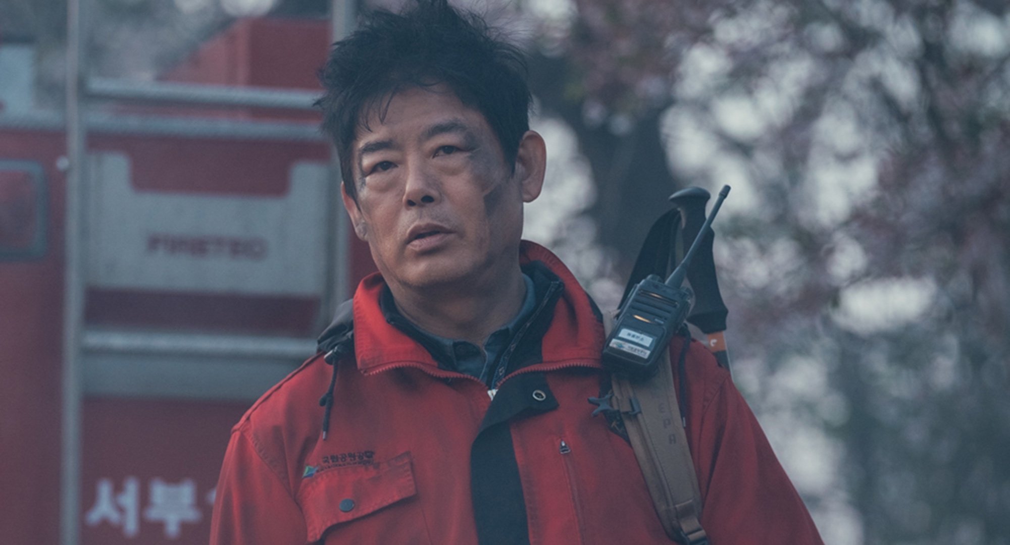 Character Jo Dae-jin for 'Jirisan' Episode 8 covered in soot and wearing red ranger jacket