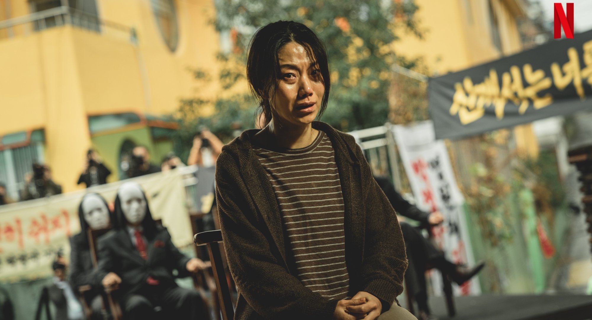 Character Park Jung-Ja for 'Hellbound' K-drama sitting in front of audience.