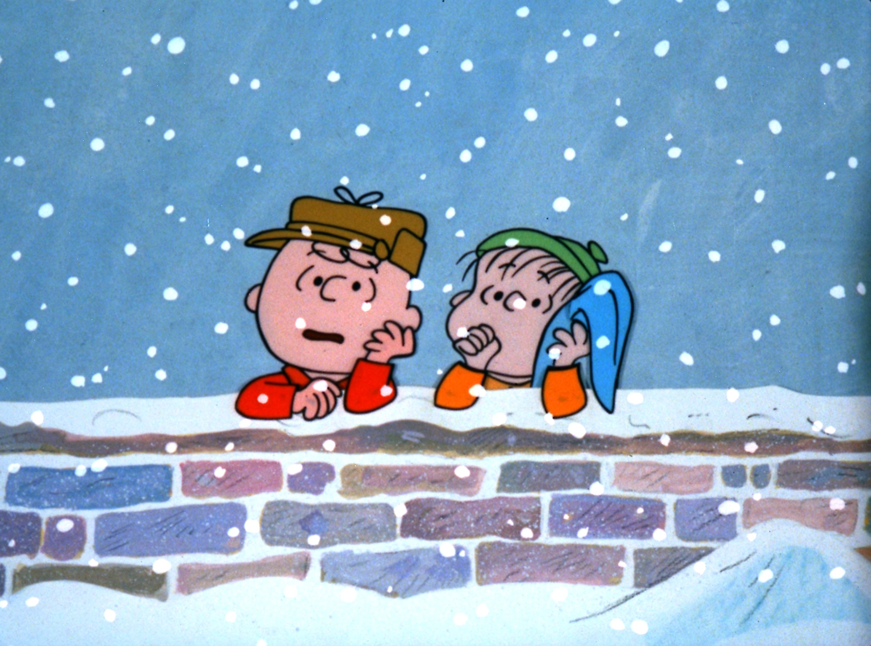 Charlie Brown and Linus Van Pelt leaning on a brick wall in the snow in 'A Charlie Brown Christmas'
