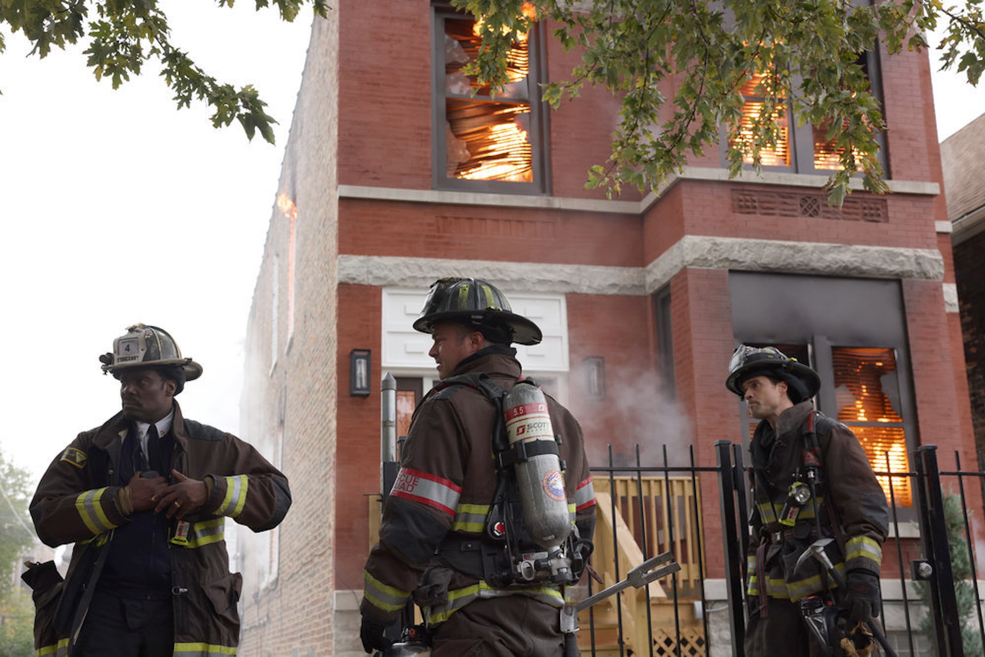 Eamonn Walker as Wallace Boden, Taylor Kinney as Kelly Severide, and Brett Dalton as Jason Pelham in firefighting uniforms outside of a burning building in 'Chicago Fire' Season 10. 'Chicago Fire' will have a One Chicago holiday special in December 2021.