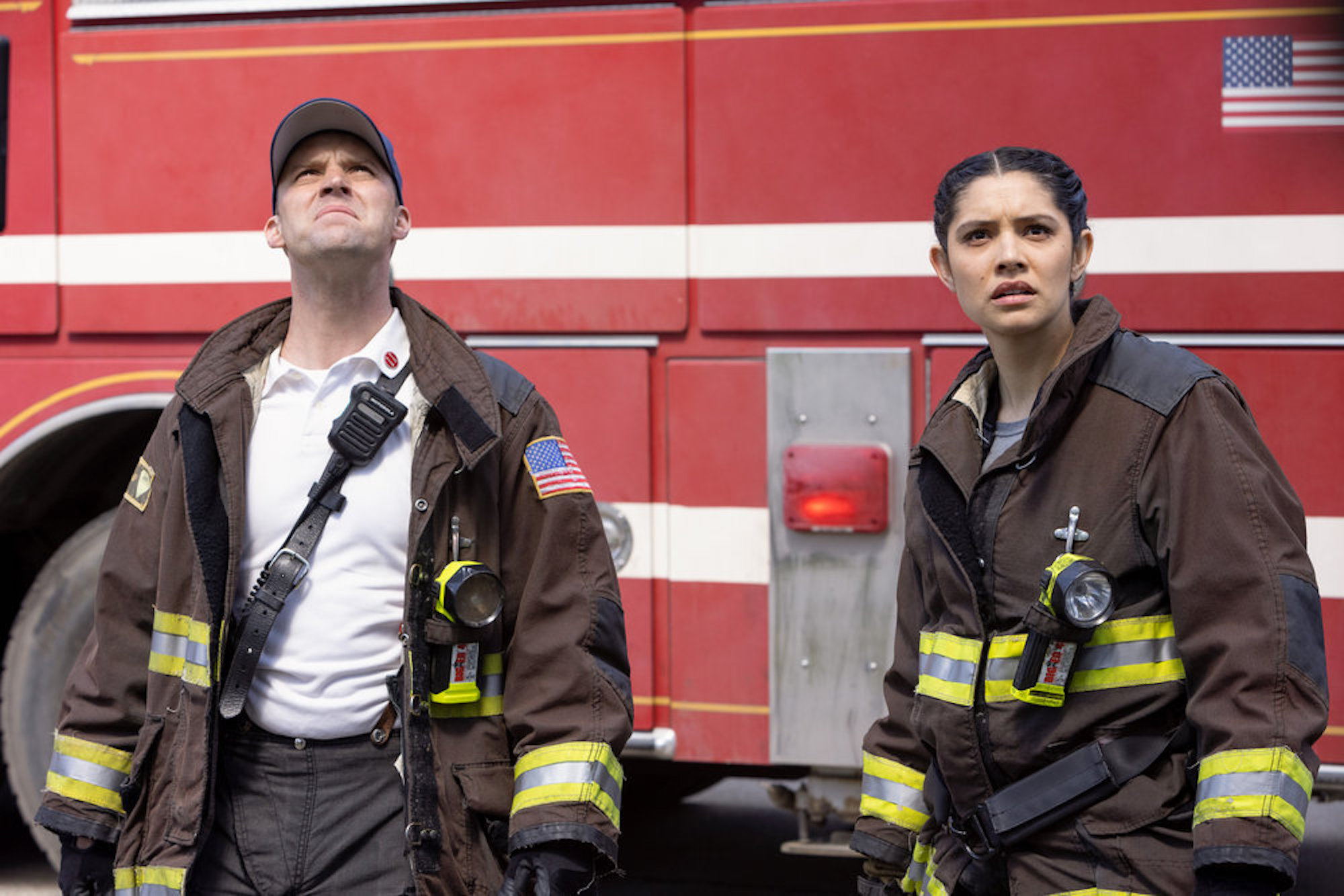Jesse Spencer as Matthew Casey and Miranda Rae Mayo as Stella Kidd from 'Chicago Fire' Season 10 dressed in firefighting uniform and looking intensely ahead