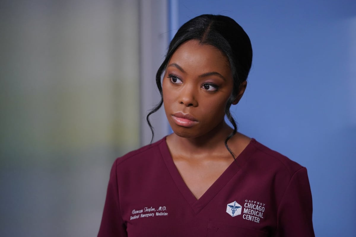 Asjha Cooper as Vanessa Taylor in Chicago Med. Vanessa is wearing maroon scrubs and looks serious.