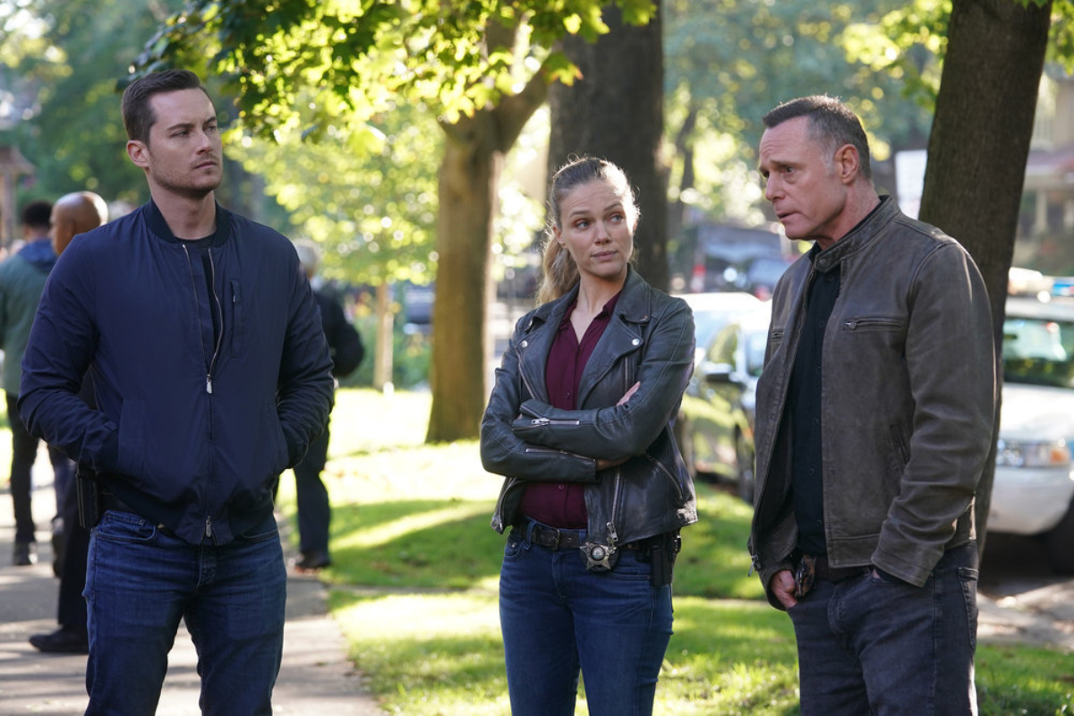 Jesse Lee Soffer as Jay Halstead, Tracy Spiridakos as Hailey, and Jason Beghe as Hank Voight in Chicago P.D. Season 9. The trio stand on the sidewalk looking concerned.