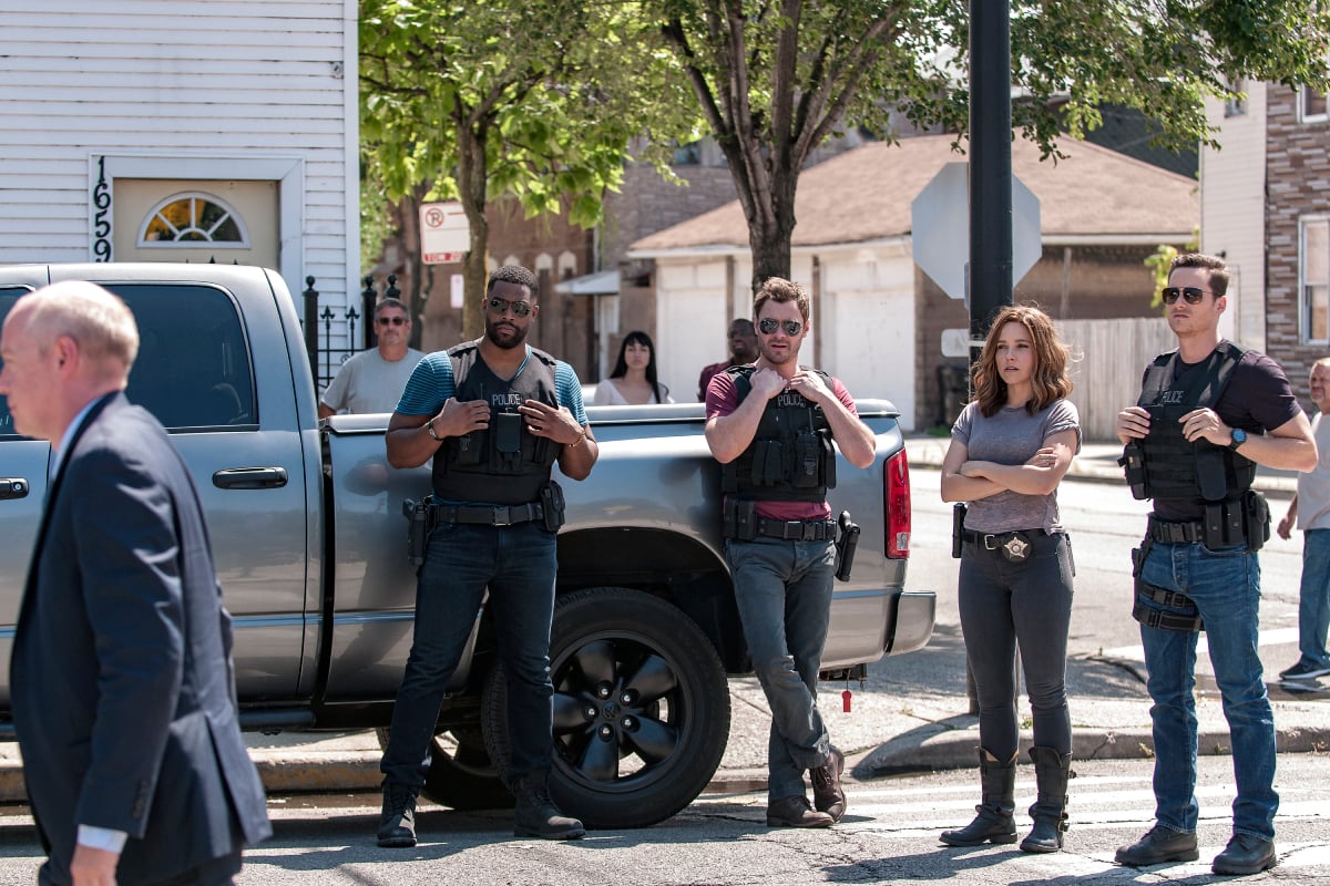 Several Chicago P.D. characters stand outside wearing bulletproof vests.