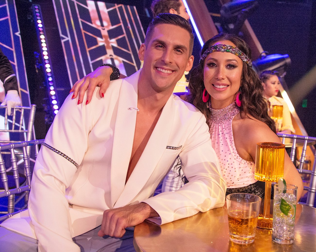 Cody Rigsby and Cheryl Burke sitting at a high top during 'Dancing with the Stars' theme night for Queen