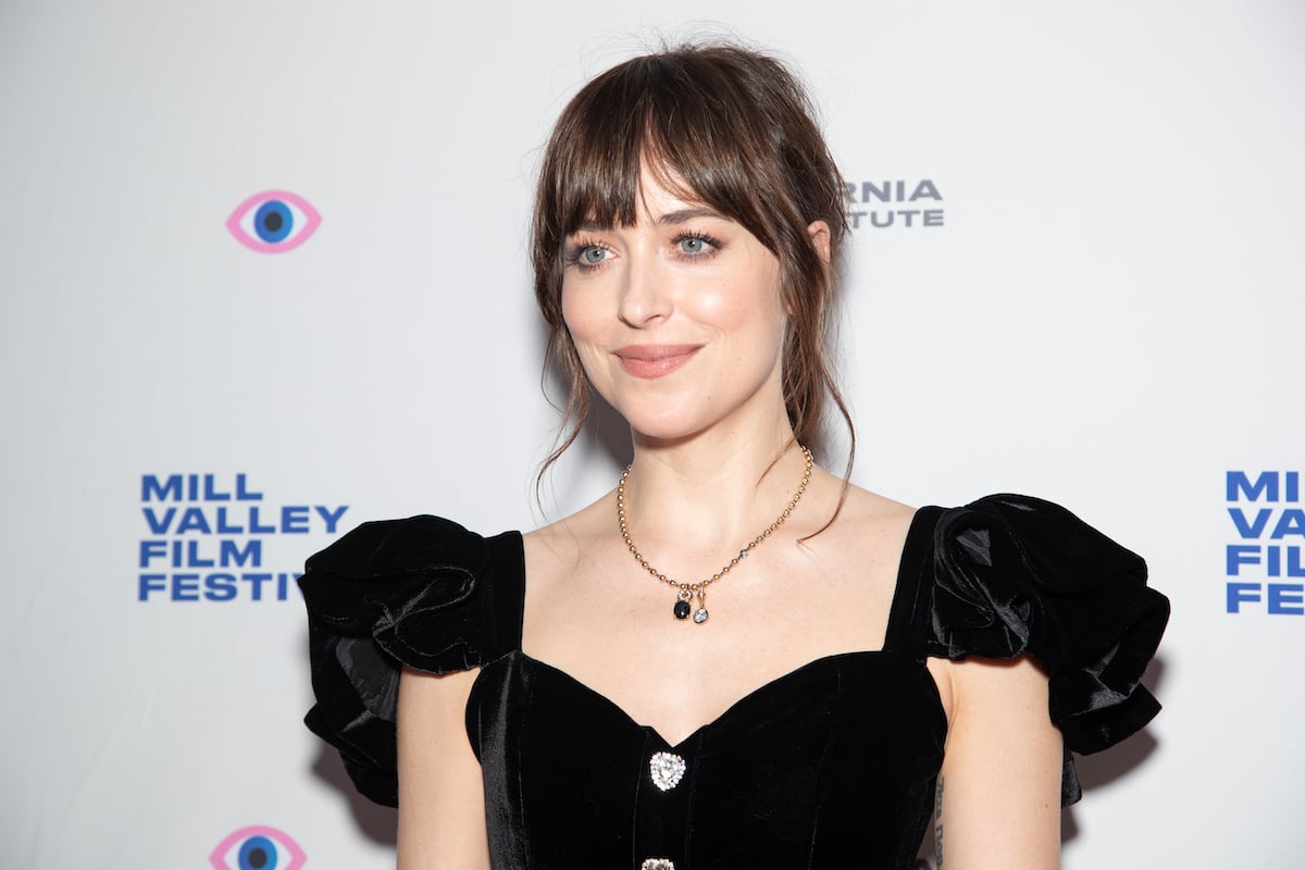 Dakota Johnson smiling in front of a white background