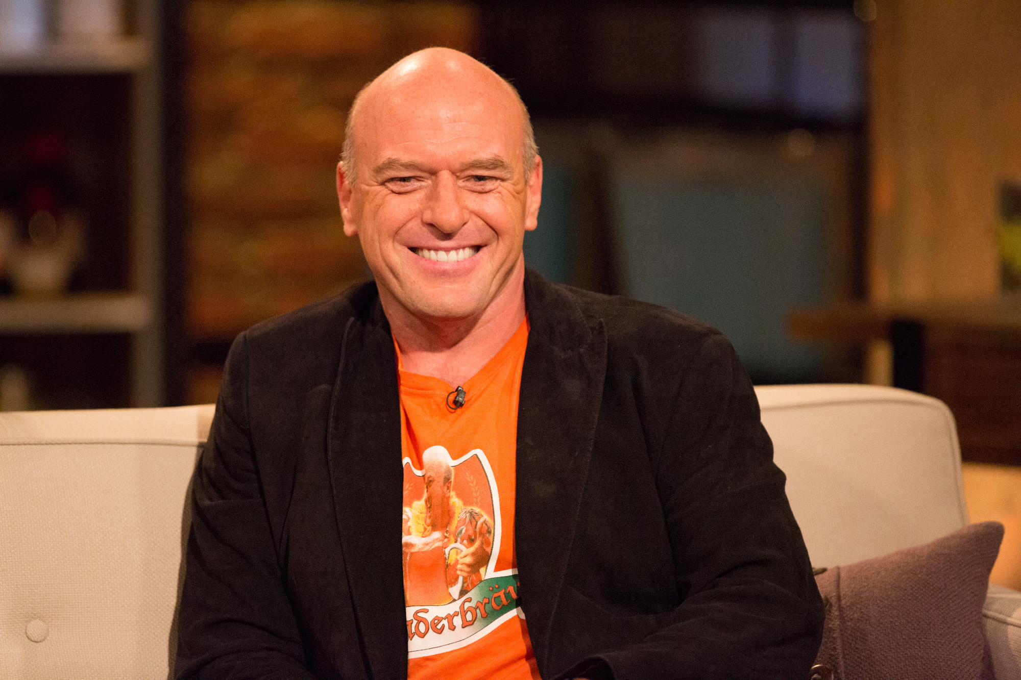 Dean Norris, who plays Hank Shrader from Season 1 to Season 5 of 'Breaking Bad.' He's on a talk show called 'Talking Bad' and wearing an orange shirt.
