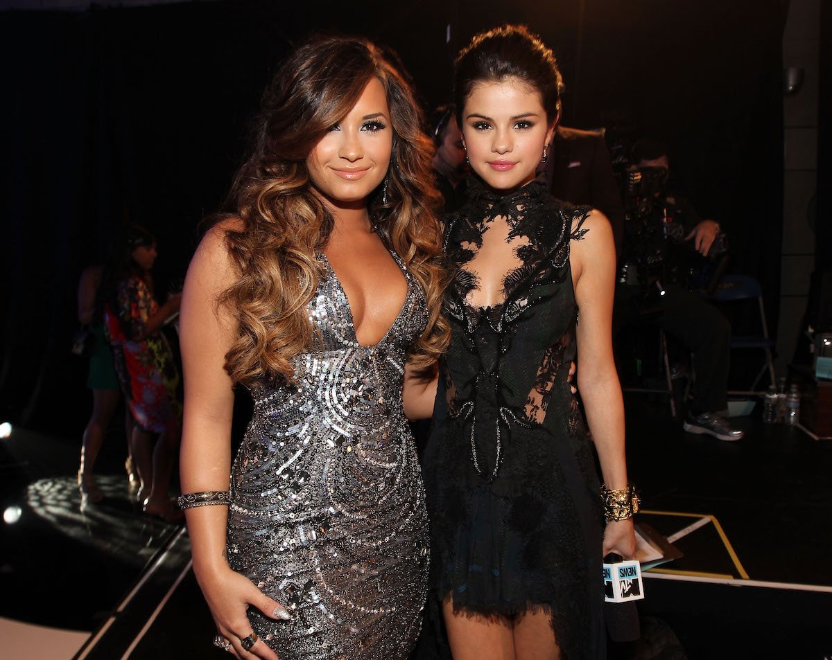 Demi Lovato and Selena Gomez pose together at an event.