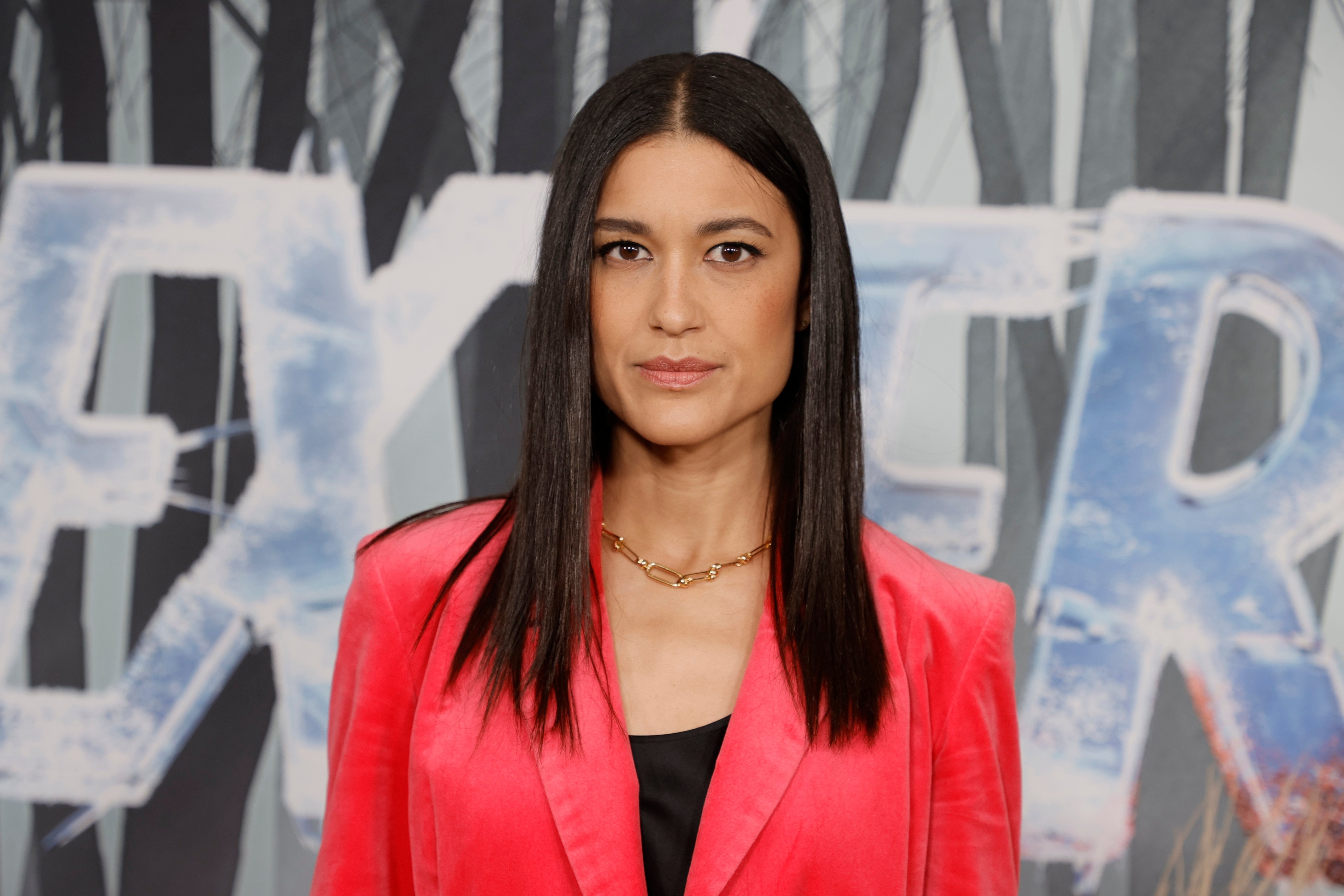 Julia Jones as Angela Bishop in Dexter: New Blood. Jones is wearing a pink blazer and gold necklace.