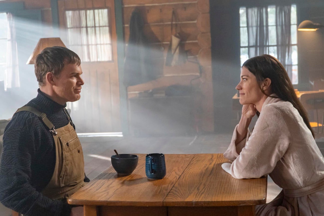 Michael C. Hall as Dexter Morgan and Jennifer Carpenter as Deb Morgan sitting together at a table in a cabin in 'Dexter: New Blood'