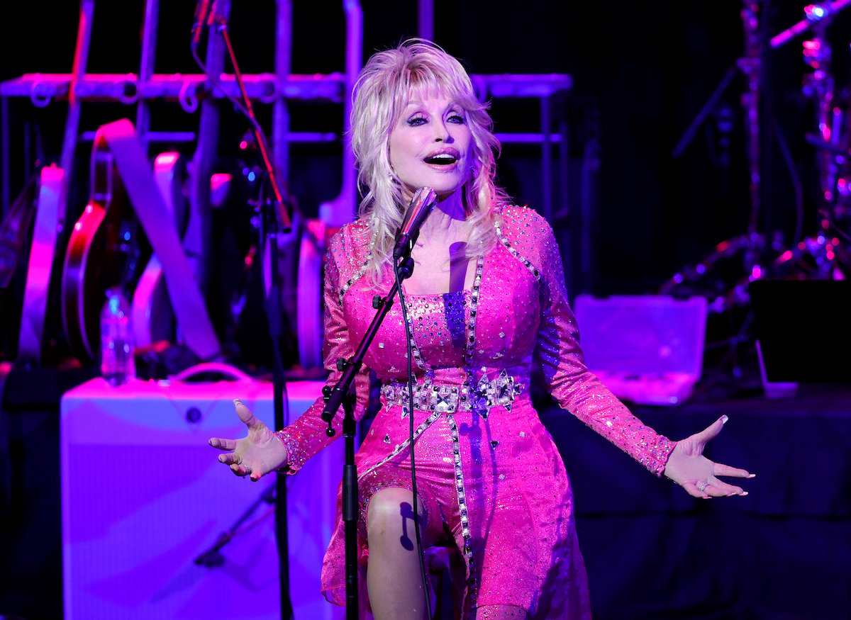 Dolly Parton performs on stage wearing pink.