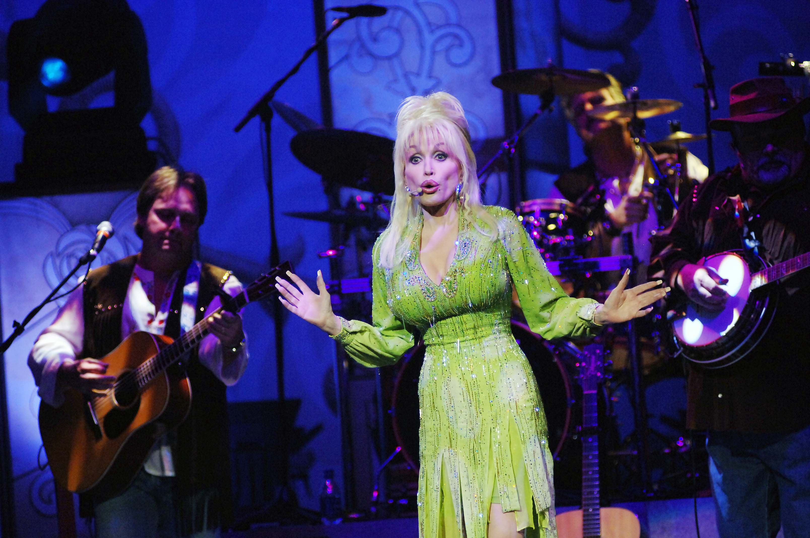 Dolly Parton performs on stage in a lime green dress.