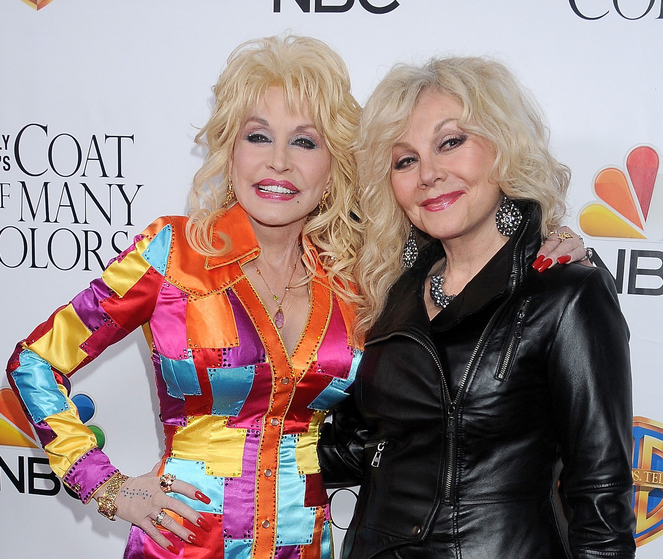 Dolly Parton and her sibling Stela Parton. Dolly Parton wears a rainbow jacket and Stella Parton wears a black leather jacket.