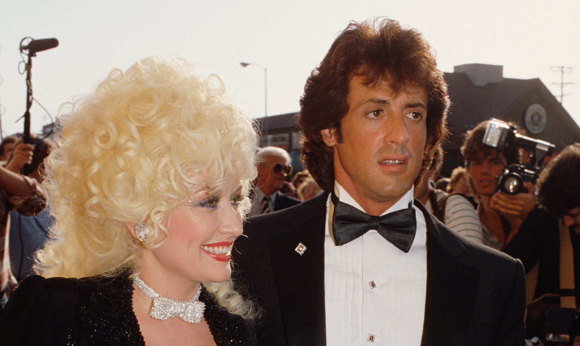 Dolly Parton smiles as she and Sylvester Stallone arrive at the premiere of 'Rhinestone'
