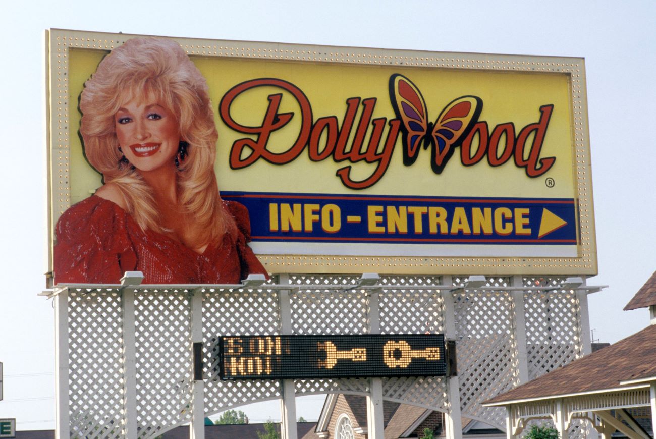 A yellow billboard for Dollywood with an image of Dollywood in a red dress.