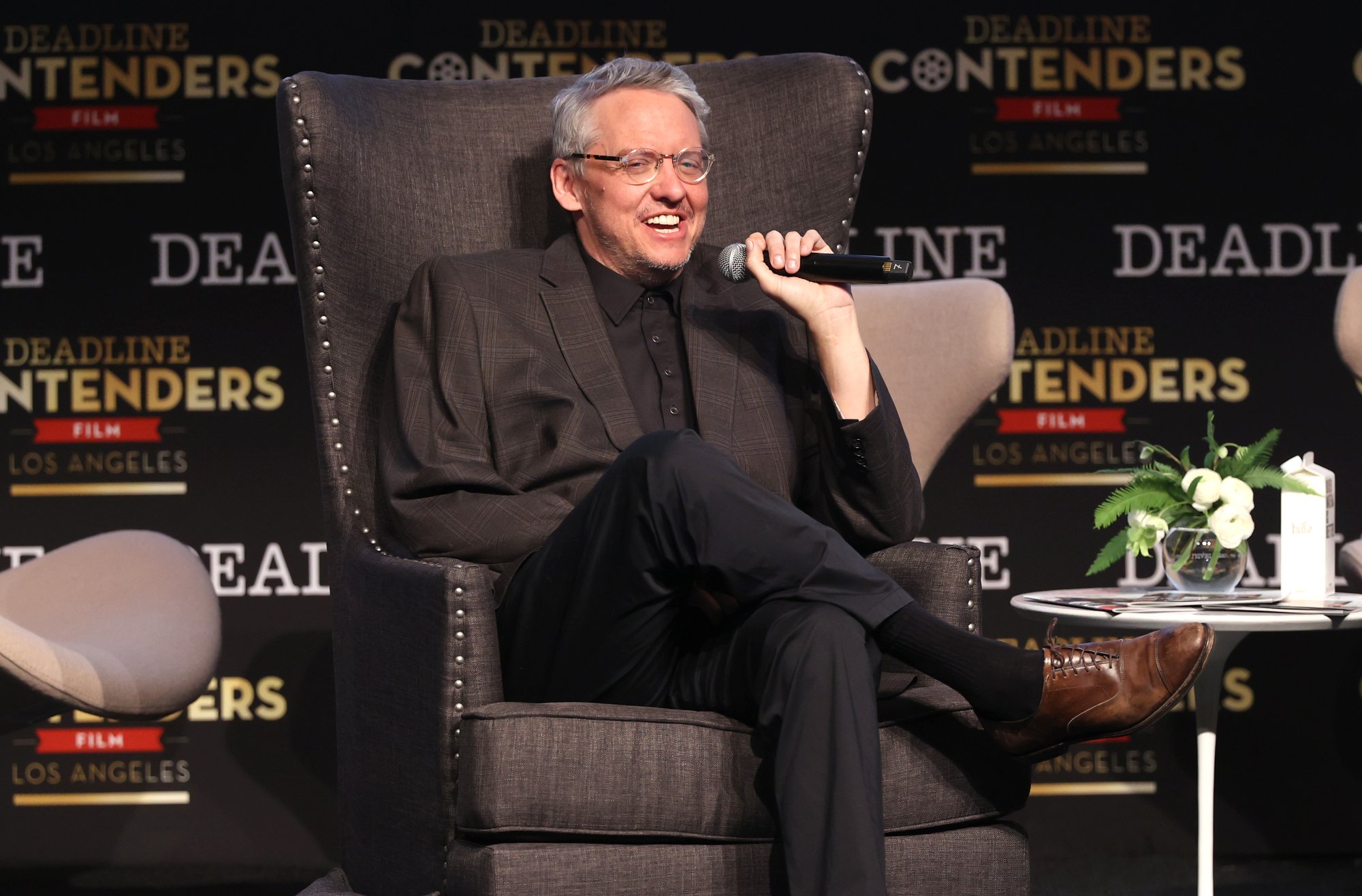 'Don't Look Up' director, writer, and producer Adam McKay on a gray sofa chair with a microphone