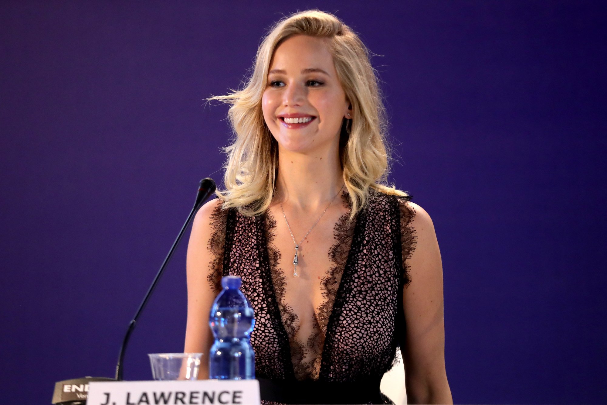 'Don't Look Up' star Jennifer Lawrence wearing a black dress behind a microphone