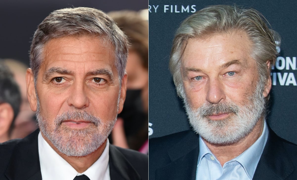 George Clooney (L), Alec Baldwin (R). Clooney poses for cameras in a black suit with a crowd behind him. Baldwin stands in a blue suit and shirt in front of a dark grey backdrop.