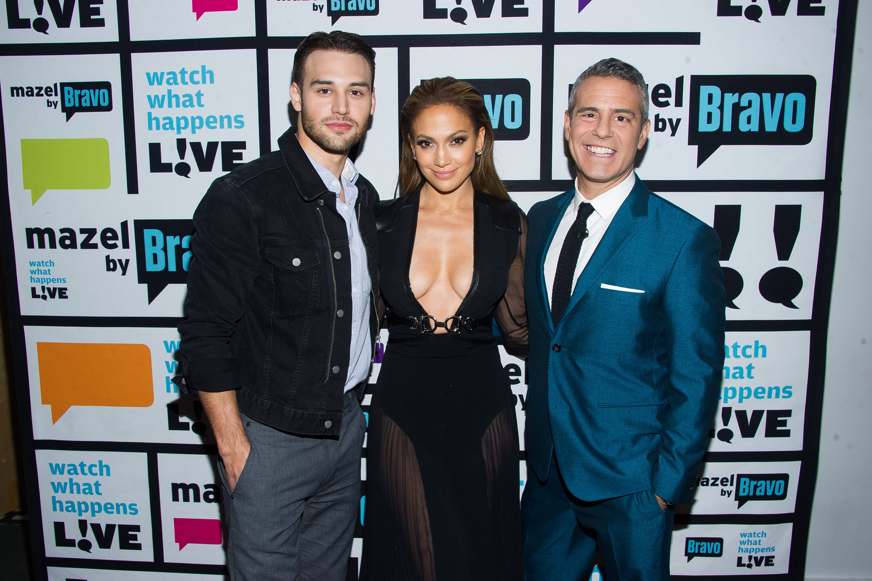 Ryan Guzman, Jennifer Lopez and Andy Cohen pose in front of a wall during 'Watch What Happens Live'