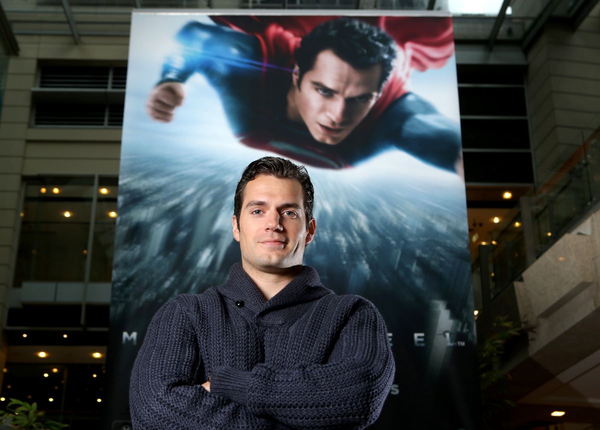 Henry Cavill standing in front of Superman poster