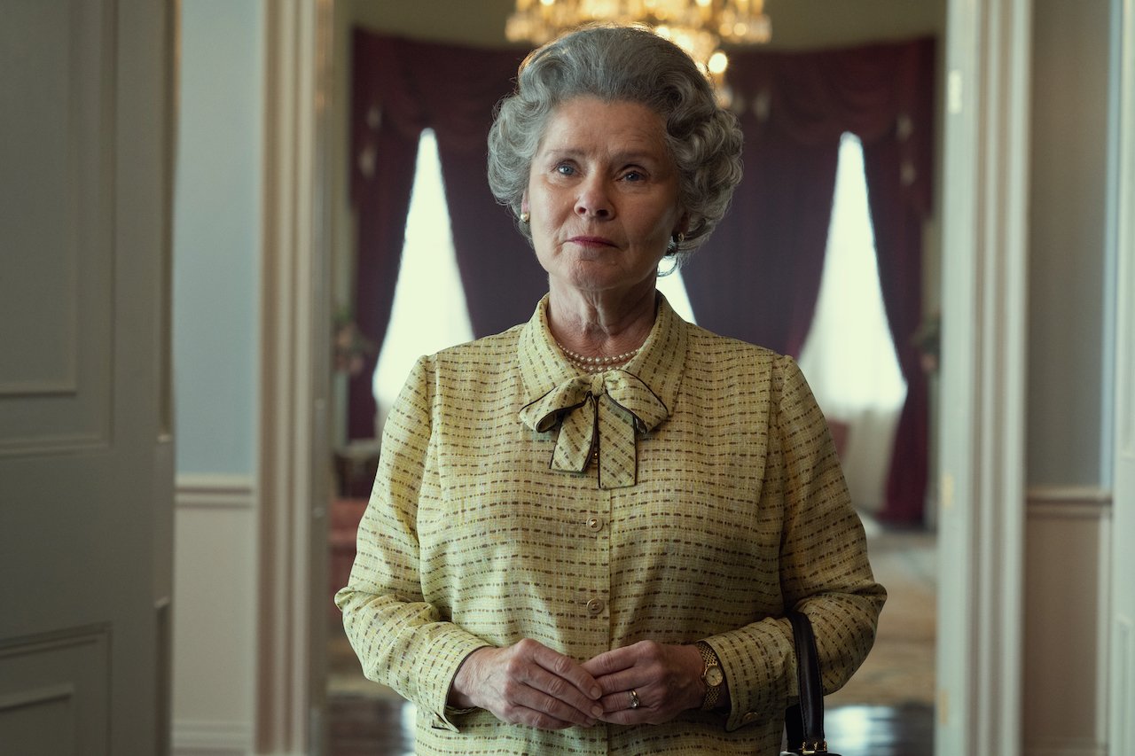 Imelda Staunton of 'The Crown' wears a yellow outfit standing in the palace.